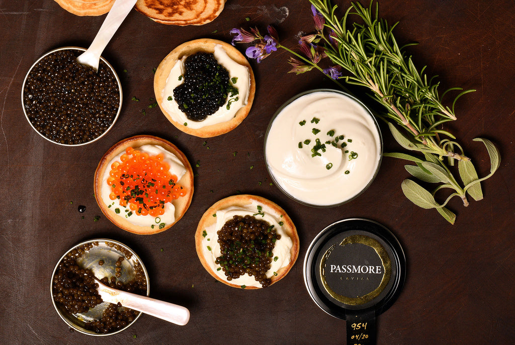 caviar and roe sampler open on table with herbs, blinis, and creme fraiche